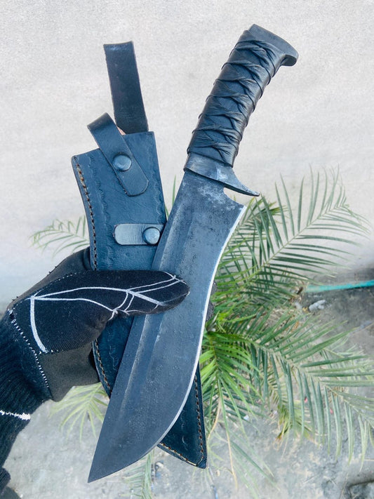 Close view of the 10 inch blade and guard detailing on a handmade hunting knife with leather grip and forge-scale finish.