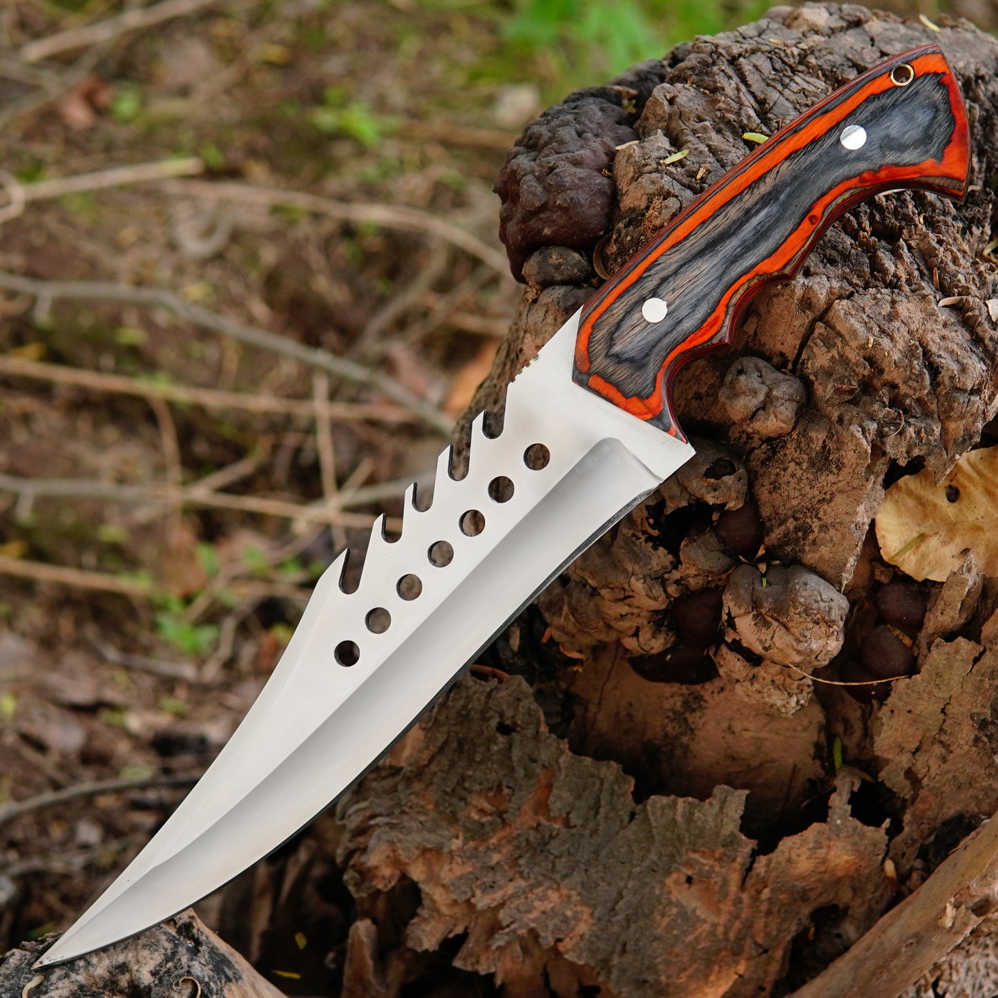 Outdoor lifestyle photo showing the knife on natural ground with trees and leaves creating a rugged survival setup that highlights its use as a dependable hunting and camping tool.