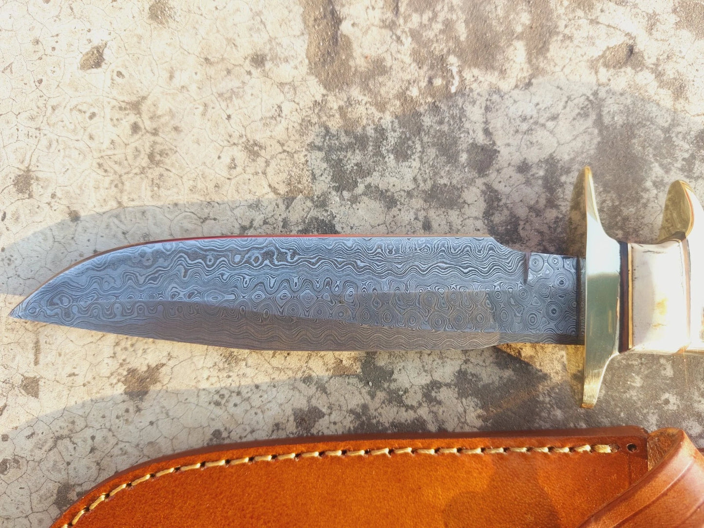 Outdoor damascus steel knife with natural handle and brass guard. Each blade is forged by hand, making the swirling damascus pattern unique to every piece. Paired with a durable stitched leather sheath, this knife makes an excellent choice for hunting trips, camping gear, or as a collectible handmade blade.