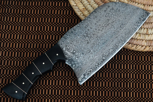 This Damascus Serbian knife features a full tang cleaver blade and a glossy black buffalo horn handle. Handmade for chefs and outdoor cooking lovers, it combines durability with beauty. Personalisation is included free, ideal for gifts.
