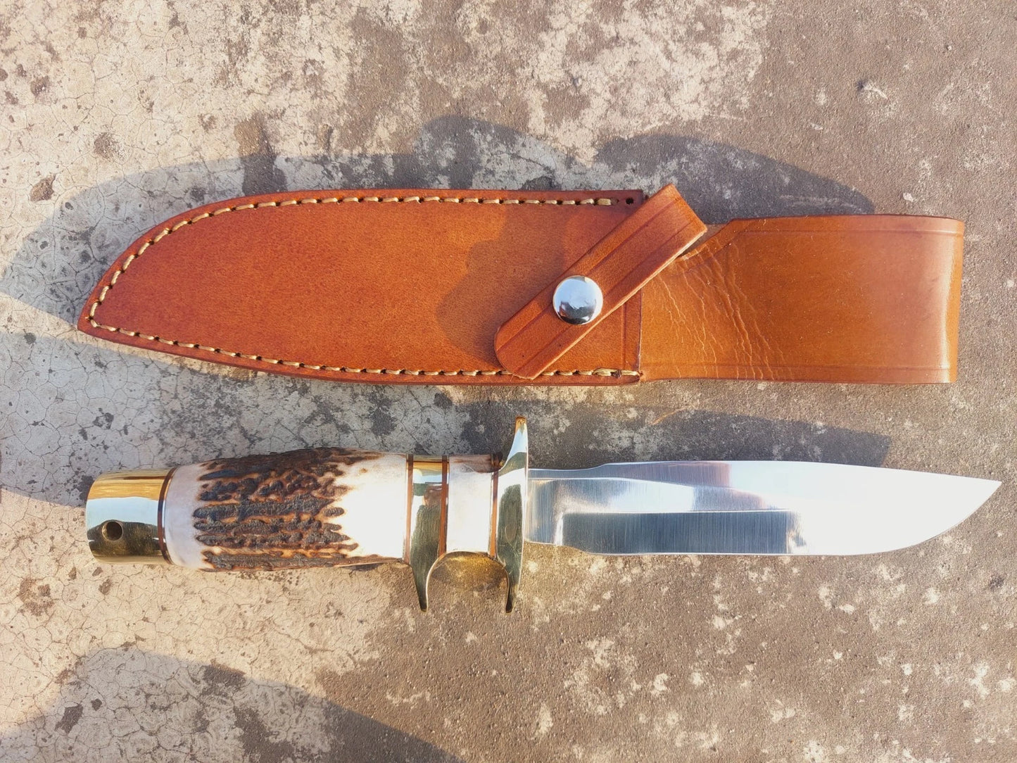 Collector hunting knife featuring mirror-polished carbon steel blade and natural handle grip. With brass guard and butt cap, it blends strength and elegance. Includes a stitched leather sheath for reliable use in hunting or outdoor activities.