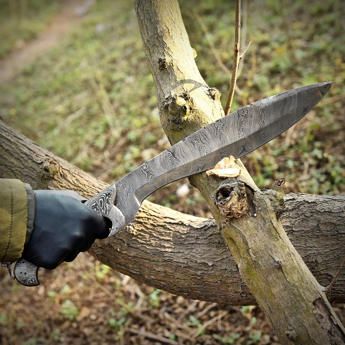 Damascus Kukri knife standing upright in a natural setting, highlighting its full tang build, artistic Damascus layers, and elegant camel bone handle. Designed for hunters, survivalists, and knife lovers who appreciate craftsmanship and reliability.