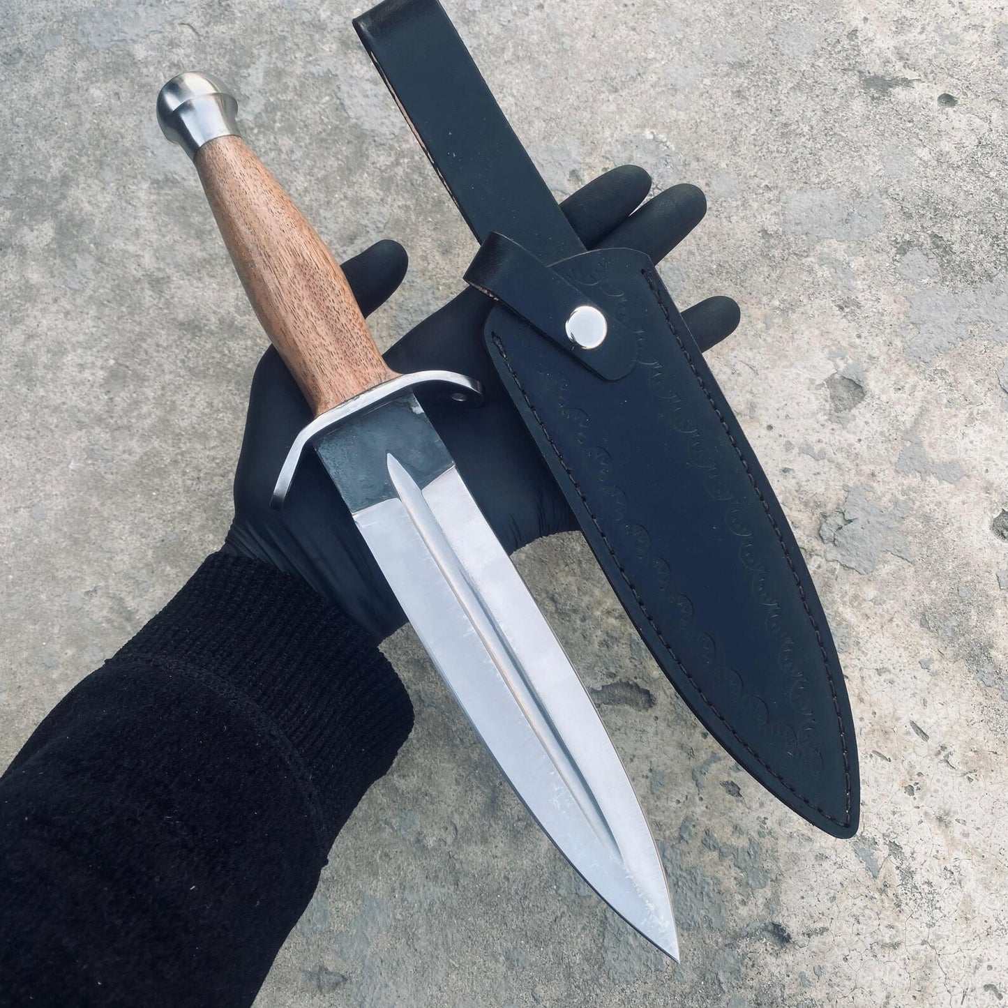 Polished dagger knife resting on rustic wooden background.