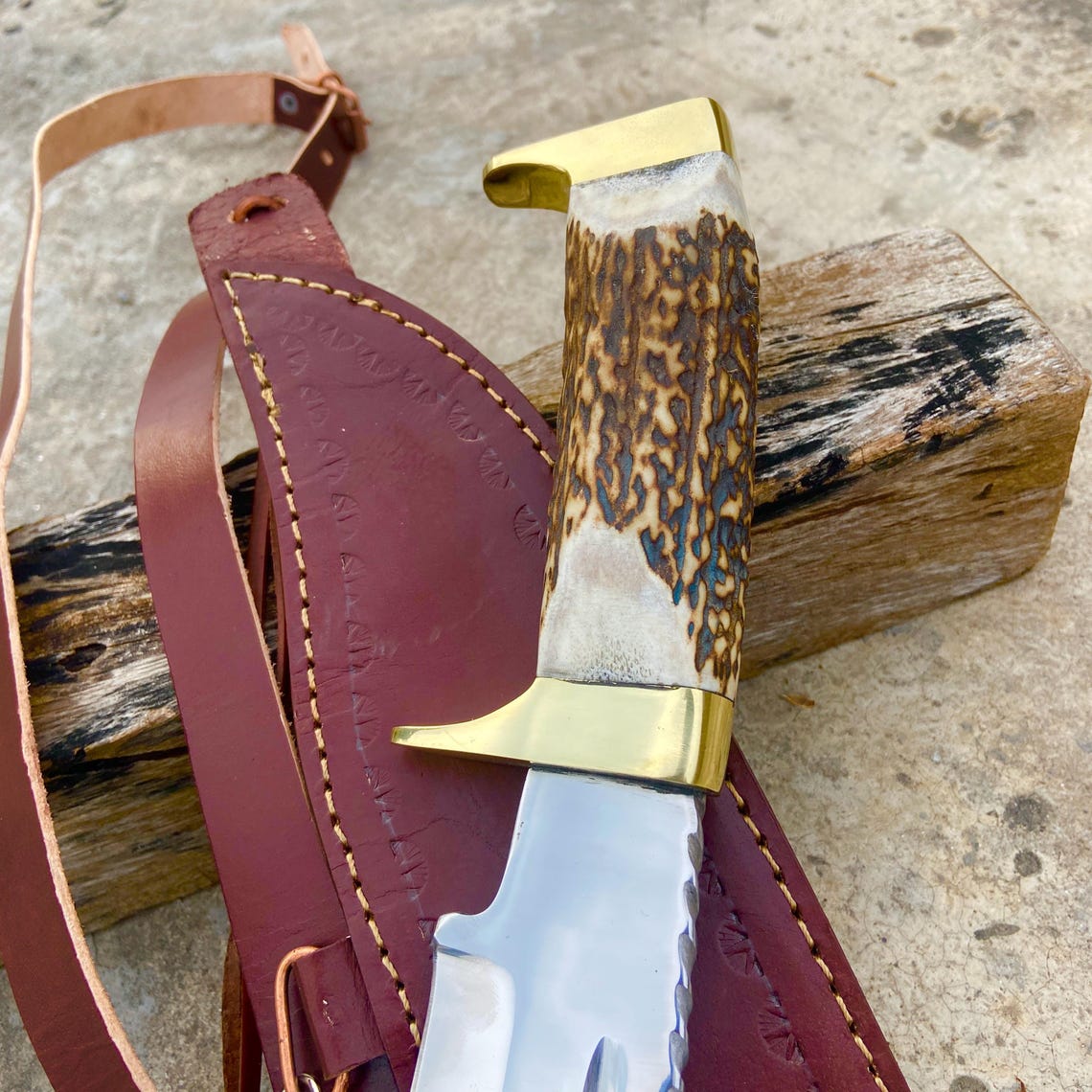 Close-up of the stag handle texture and brass guard on the handmade Bowie knife.