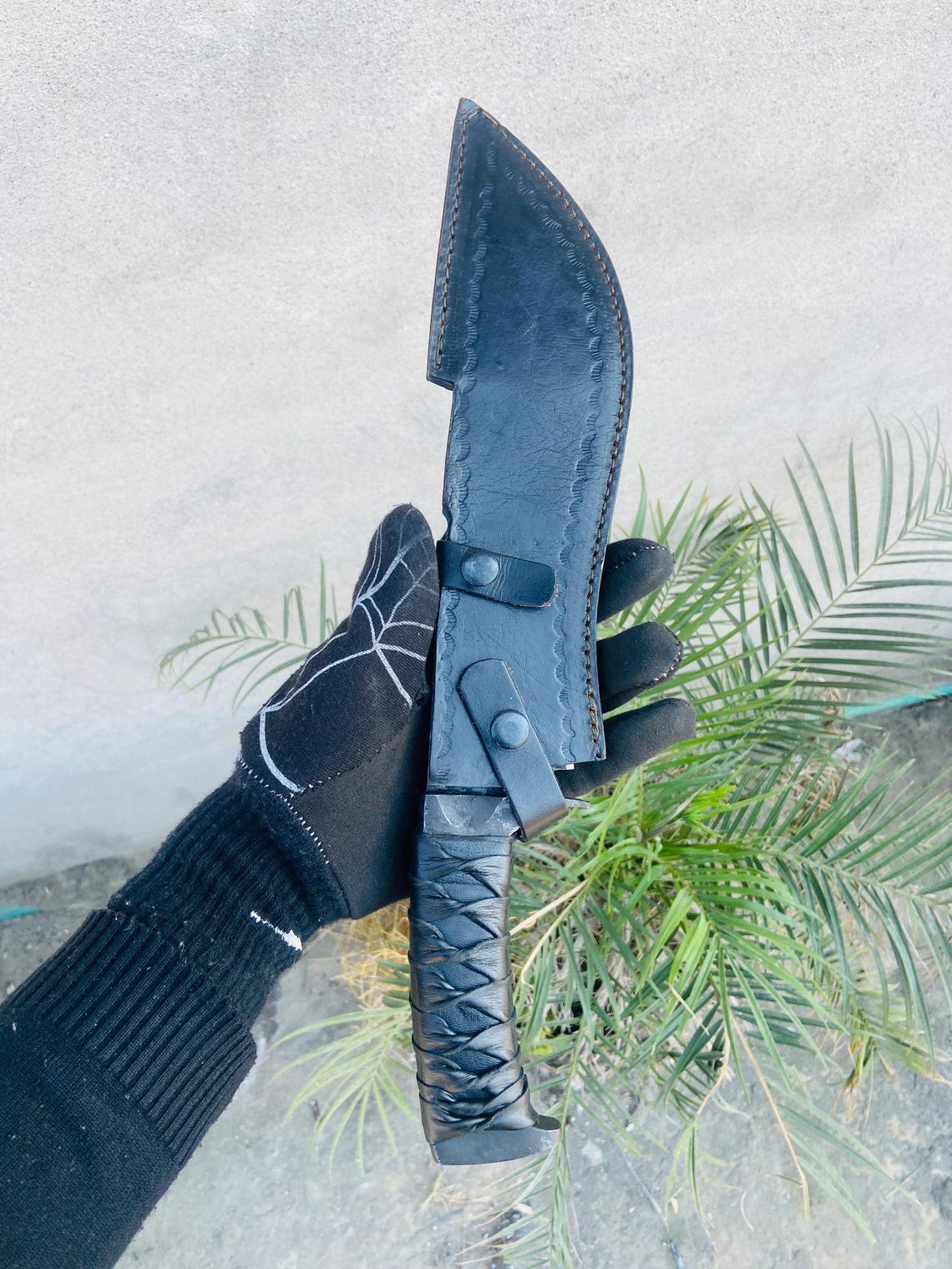 Knife fully seated in hand-stitched leather sheath with belt loop and retention strap.