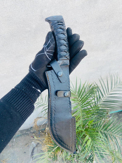 Closeup of leather-wrapped handle, guard, and retention strap on the matching belt sheath.