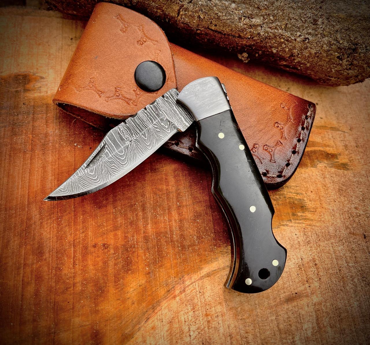 Detailed view of folding Damascus pocket knife with fish design handle and textured Damascus blade.