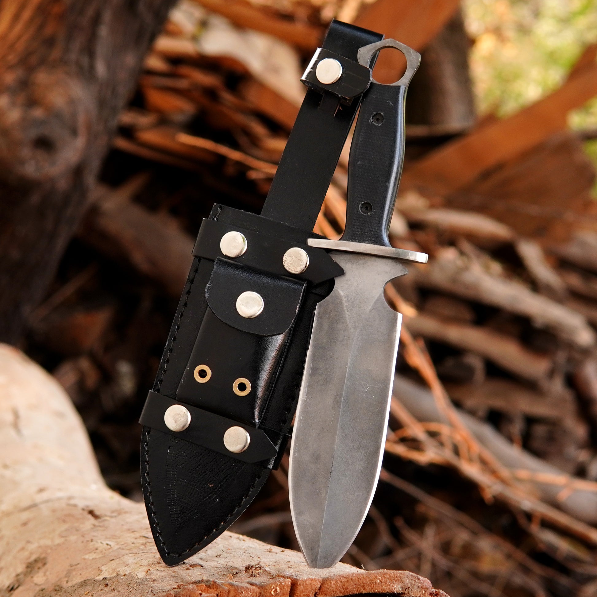 Handmade tactical Bowie knife with carbon steel blade placed on wooden log background.