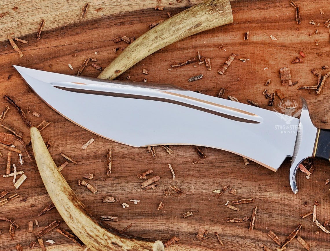 Close-up of polished D2 steel bowie blade with dual fuller detailing