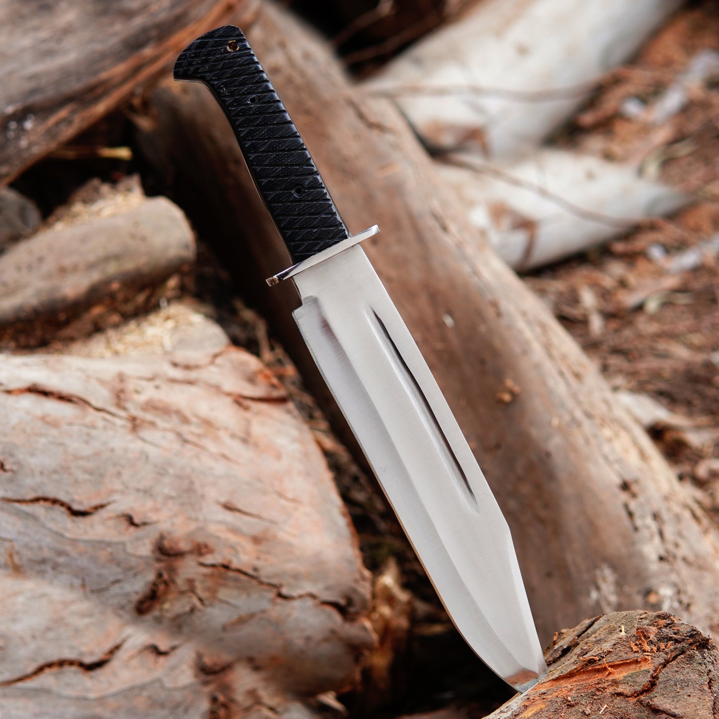 Close view of carbon steel bowie knife blade highlighting smooth grind lines and strong edge design positioned on wooden surface demonstrating outdoor utility knife suitable for camping hunting style tasks and practical outdoor activities with balanced handmade construction.