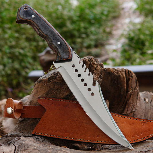 Handmade bowie hunting knife placed on natural wood outdoors showing polished high carbon steel blade and ergonomic handle made from natural material. The image highlights the strong full tang construction, clean blade finish, and outdoor-ready design suitable for camping, bushcraft, and collection use while maintaining a rugged and authentic handcrafted appearance.