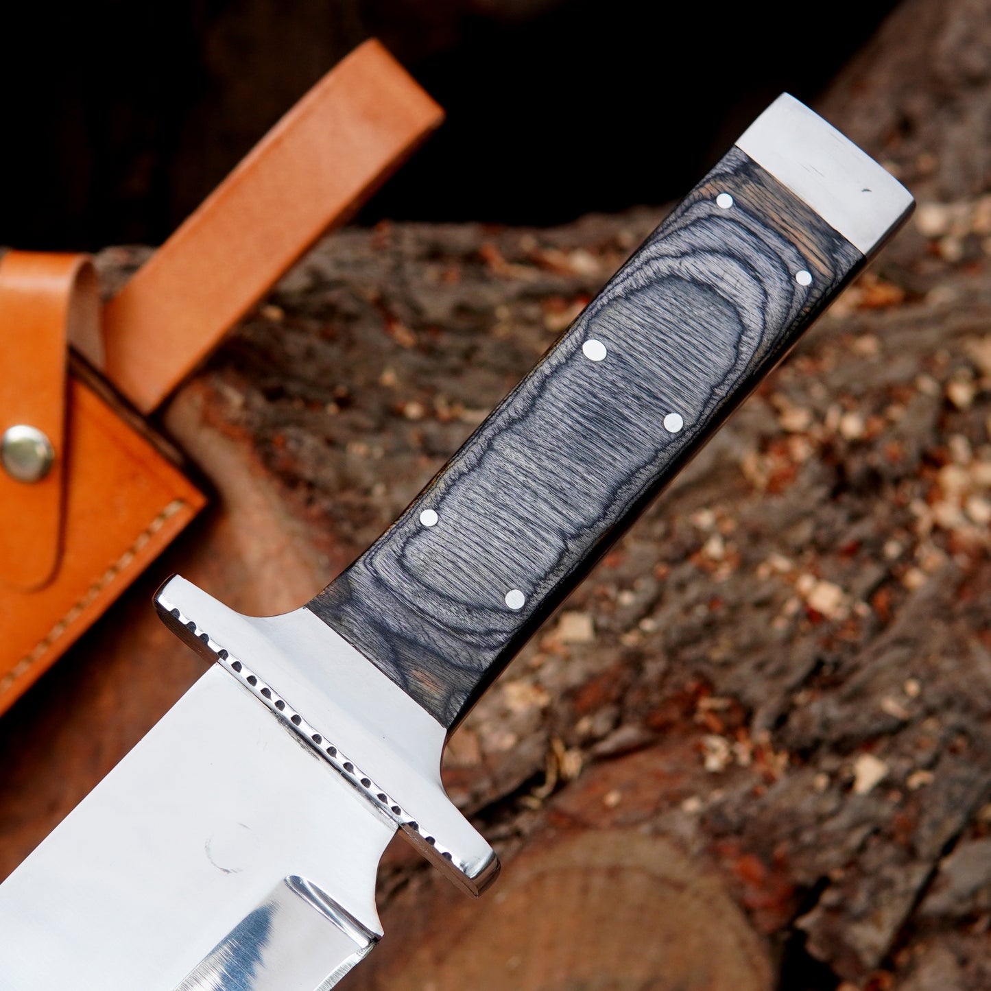 Fixed blade bowie knife photographed outdoors with polished blade reflecting natural light, emphasizing clean grind lines and durable construction. The image focuses on strength, balance, and usability for outdoor activities such as camping and bushcraft while presenting a premium handmade look suitable for collectors and enthusiasts.