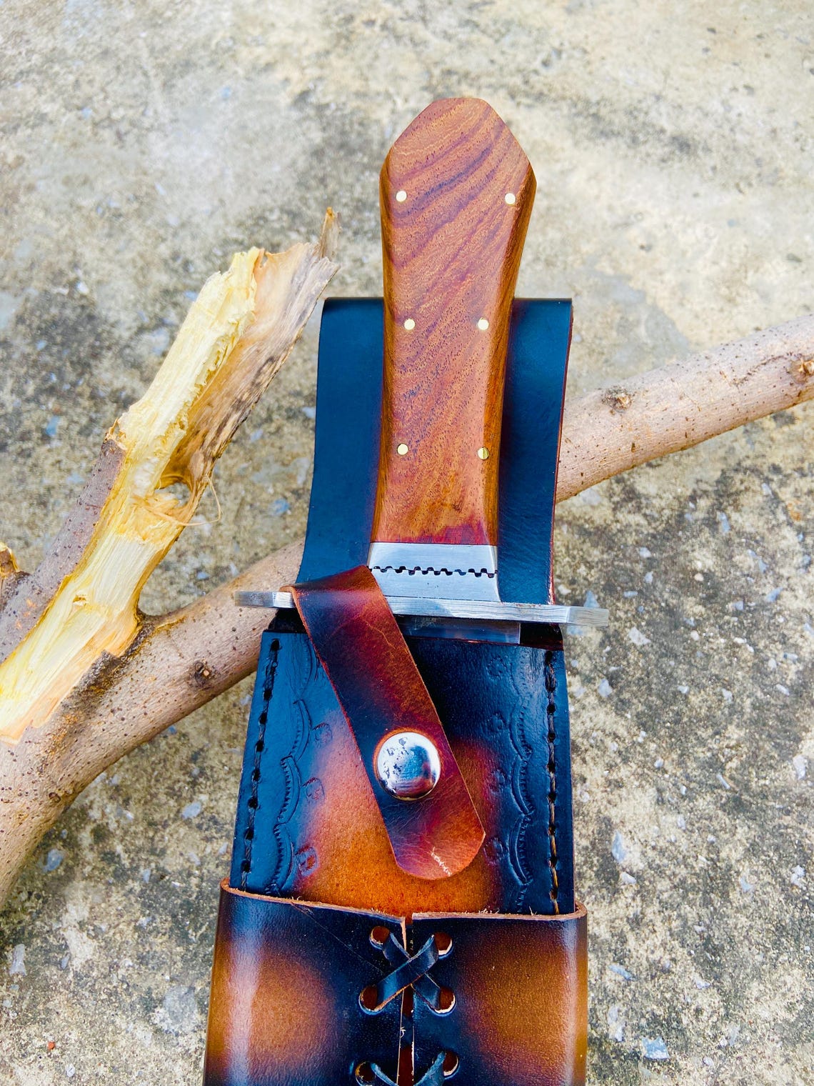 Close-up of a high-carbon steel Bowie knife featuring a glossy mirror-polished blade and rosewood coffin handle. The handcrafted leather sheath with lace design enhances its premium outdoor look. Ideal for camping, hunting, and as a handmade gift for men who value fine steel craftsmanship.