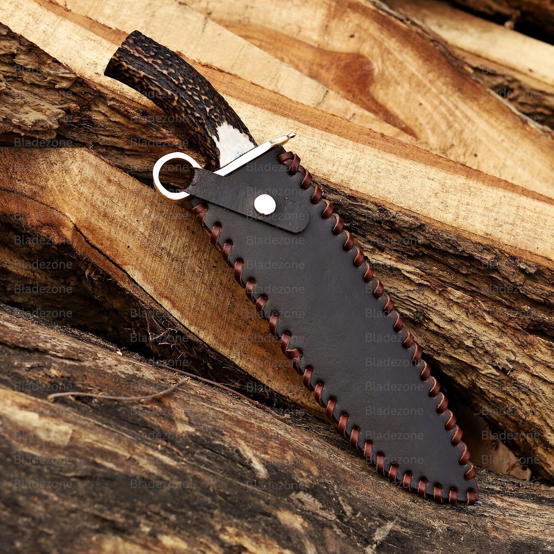This image captures the Bowie knife resting on a wooden surface with the sharp 1095 carbon steel blade in clear view. The natural stag handle curves upward, showing its rugged texture and organic appearance. The brass guard adds a classic touch to the knife’s design. The background of rough wood emphasizes the handmade and outdoor-ready nature of this unique Bowie knife.