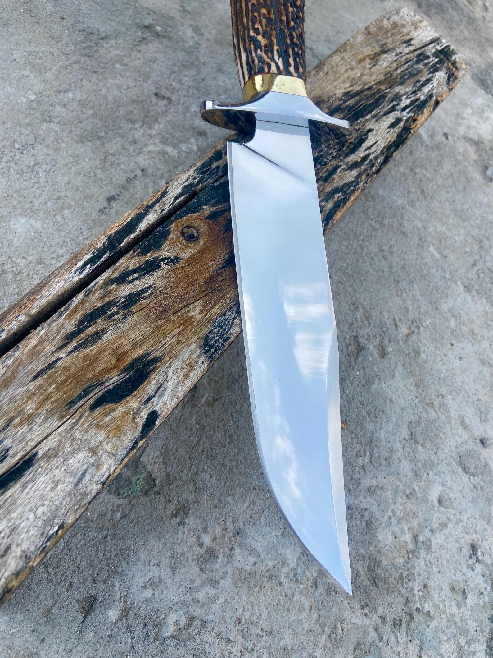 Handmade carbon steel Bowie knife with red-brown leather sheath, crafted for hunters and collectors.