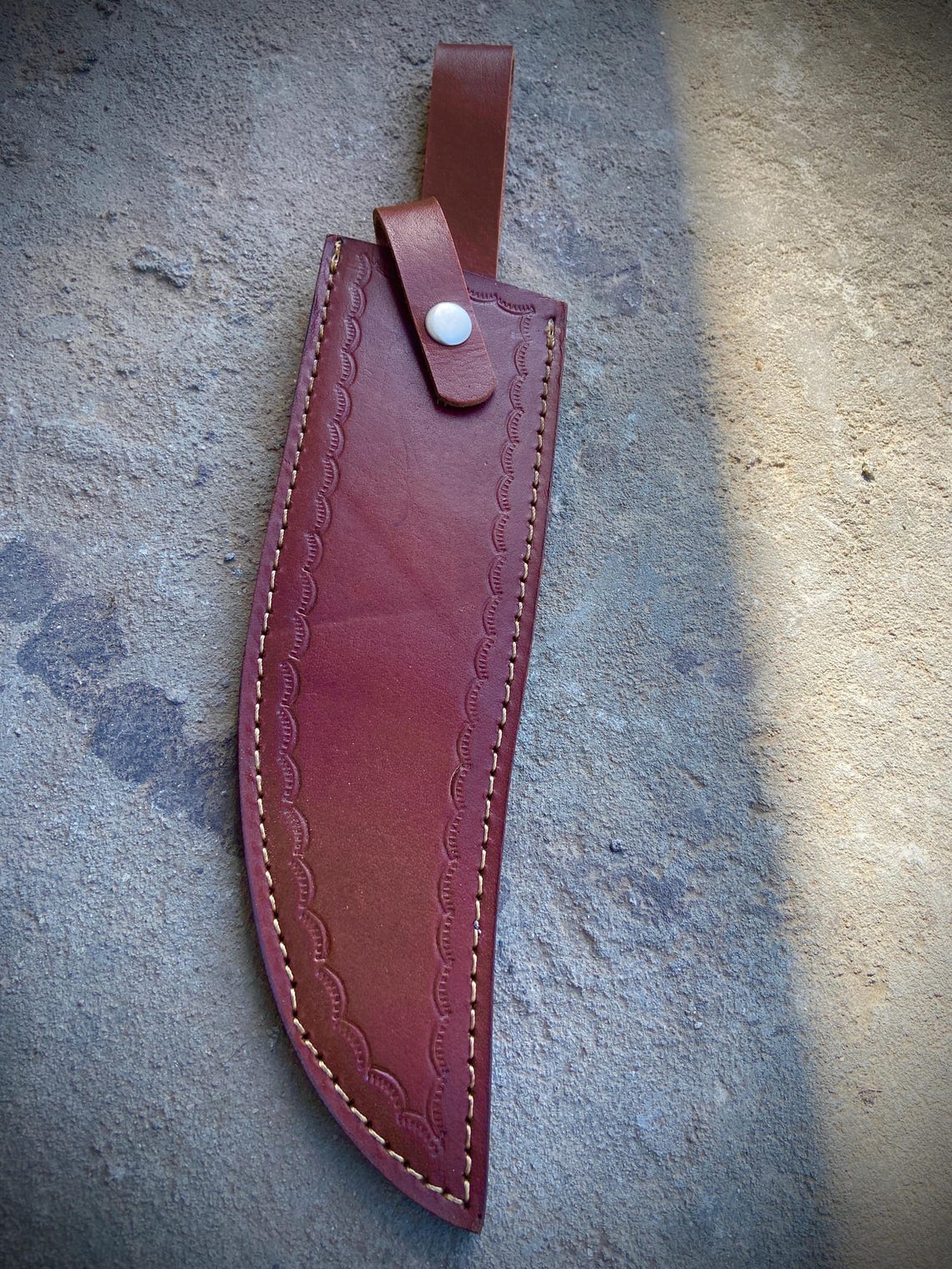 Survival bowie knife featuring polished carbon steel blade, dual-tone handle, and custom leather case.