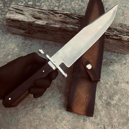 Full-length Bowie knife beside its brown hand-stitched leather sheath showing satin blade finish.