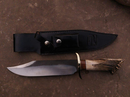 Detailed view of stag handle with brass guard on handmade carbon steel Bowie knife.