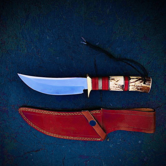 Custom hunting knife crafted from carbon steel with stag antler handle and red micarta accents. Comes with a hand-stitched sheath for safe storage, built for outdoor use and collecting.