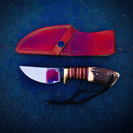Handmade carbon steel skinner hunting knife with stag antler handle, brass guard, and polished blade. Comes with a hand-stitched leather sheath, making it ideal for hunters, campers, and collectors.