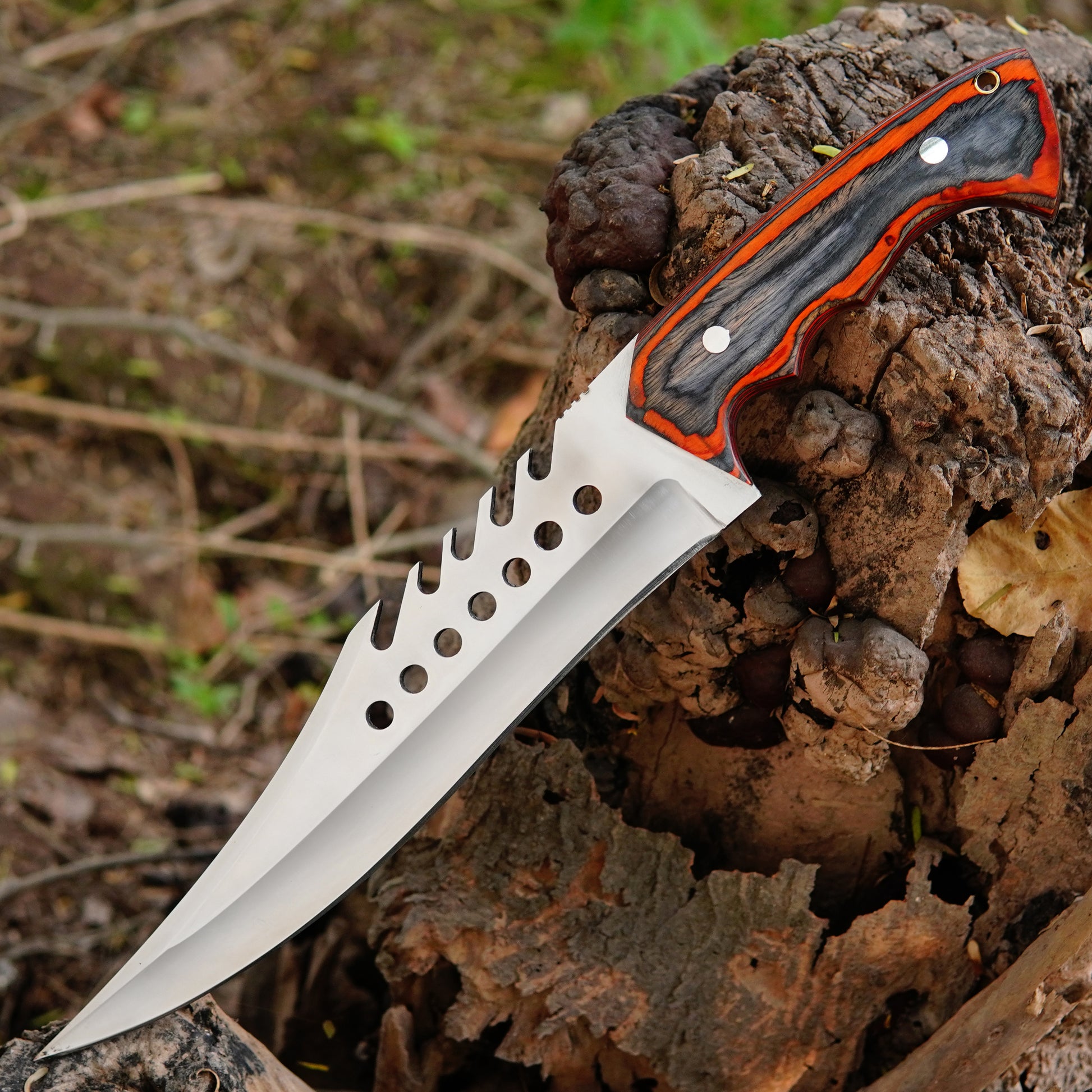 Outdoor lifestyle photo showing the knife on natural ground with trees and leaves creating a rugged survival setup that highlights its use as a dependable hunting and camping tool.