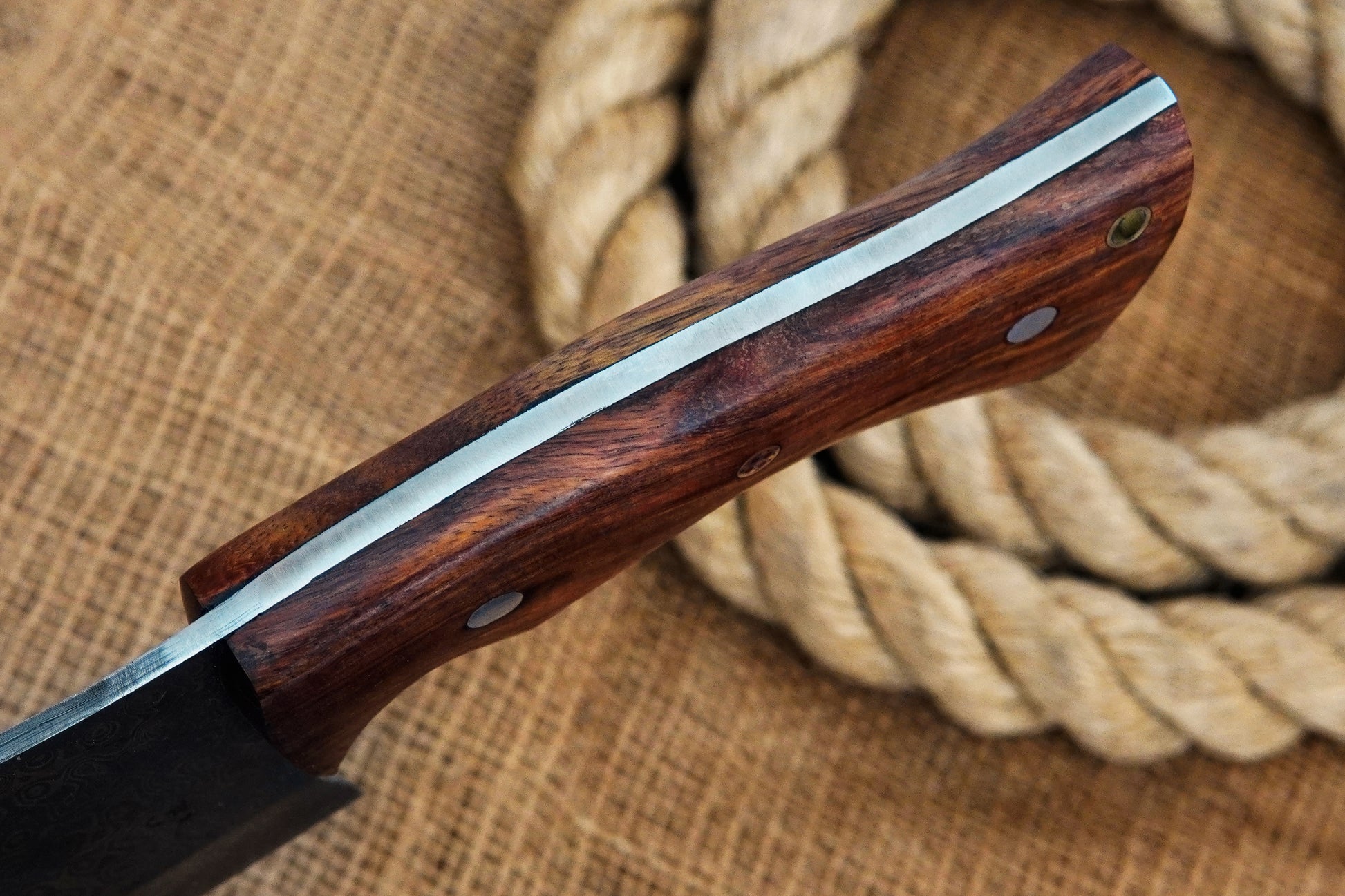 A Serbian-style chef cleaver handmade from Damascus steel with a full tang build and rose wood handle. Excellent for slicing and chopping in the kitchen or outdoors. Includes free engraving to make it personal.
