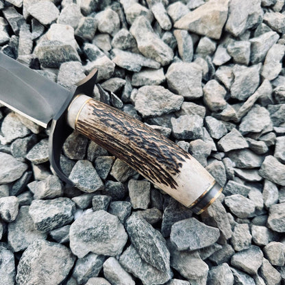 5160 spring steel Bowie knife with full tang construction and polished edge, natural stag handle, and premium black leather sheath for protection and carry.