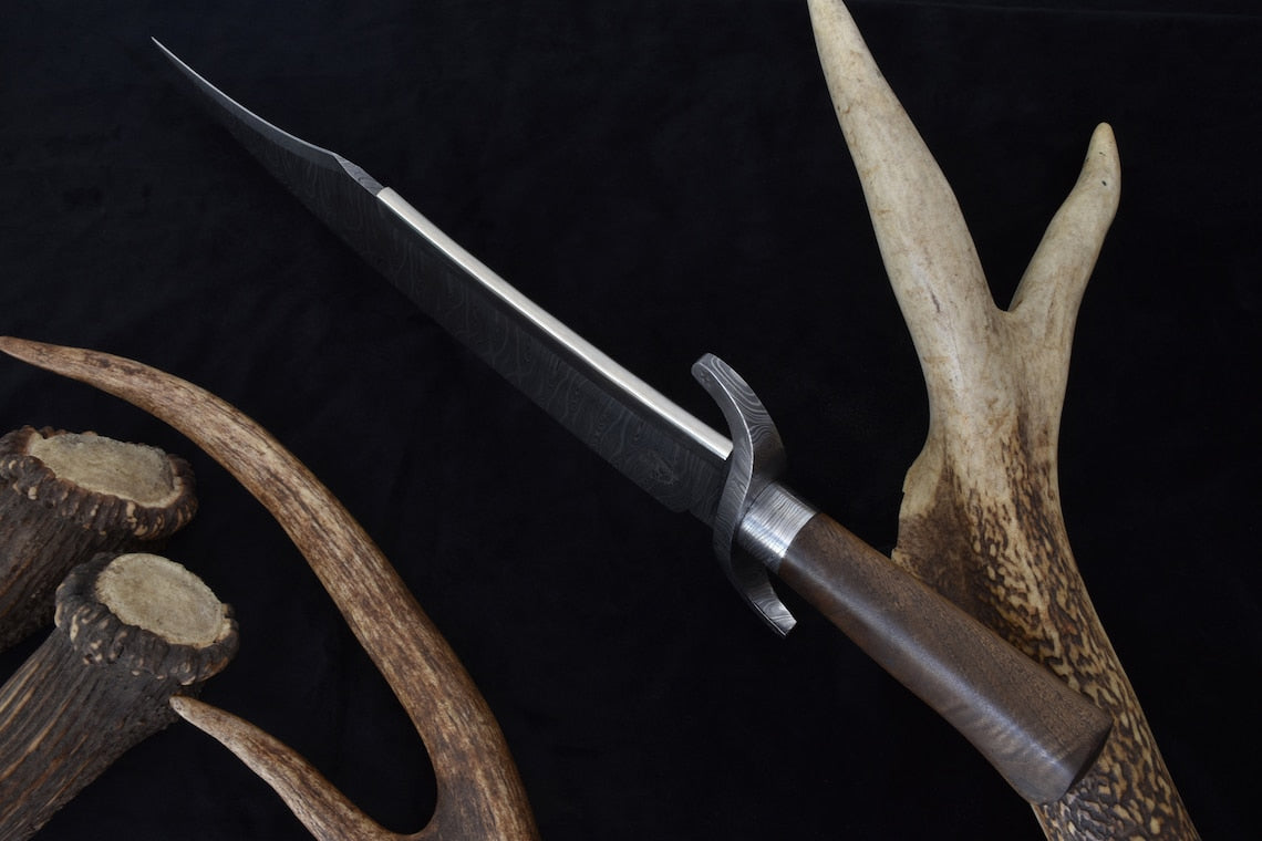 Side view of a full tang Damascus steel Texas Bowie knife showcasing detailed blade patterning, curved guard, and smooth walnut handle. Designed for strength, precision, and heritage craftsmanship.