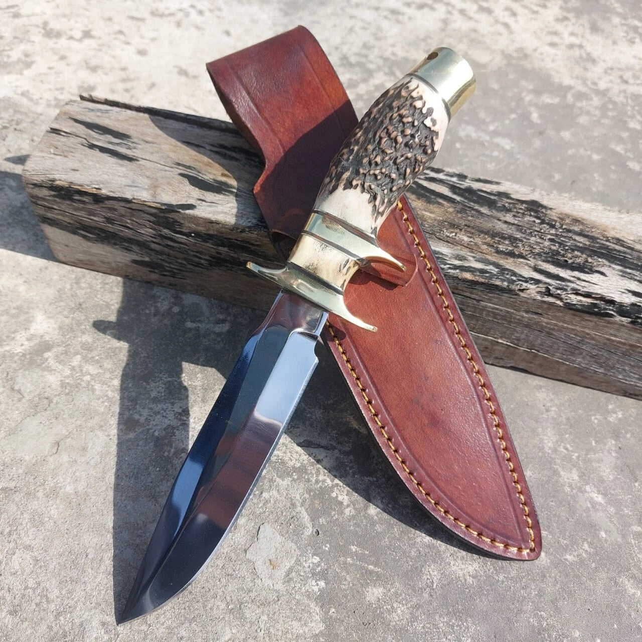 Subhilt hunting knife forged from high carbon steel with brass guard and pommel. Features a polished blade for durability and edge retention. Includes a stitched leather sheath, combining practical outdoor use with elegant craftsmanship.