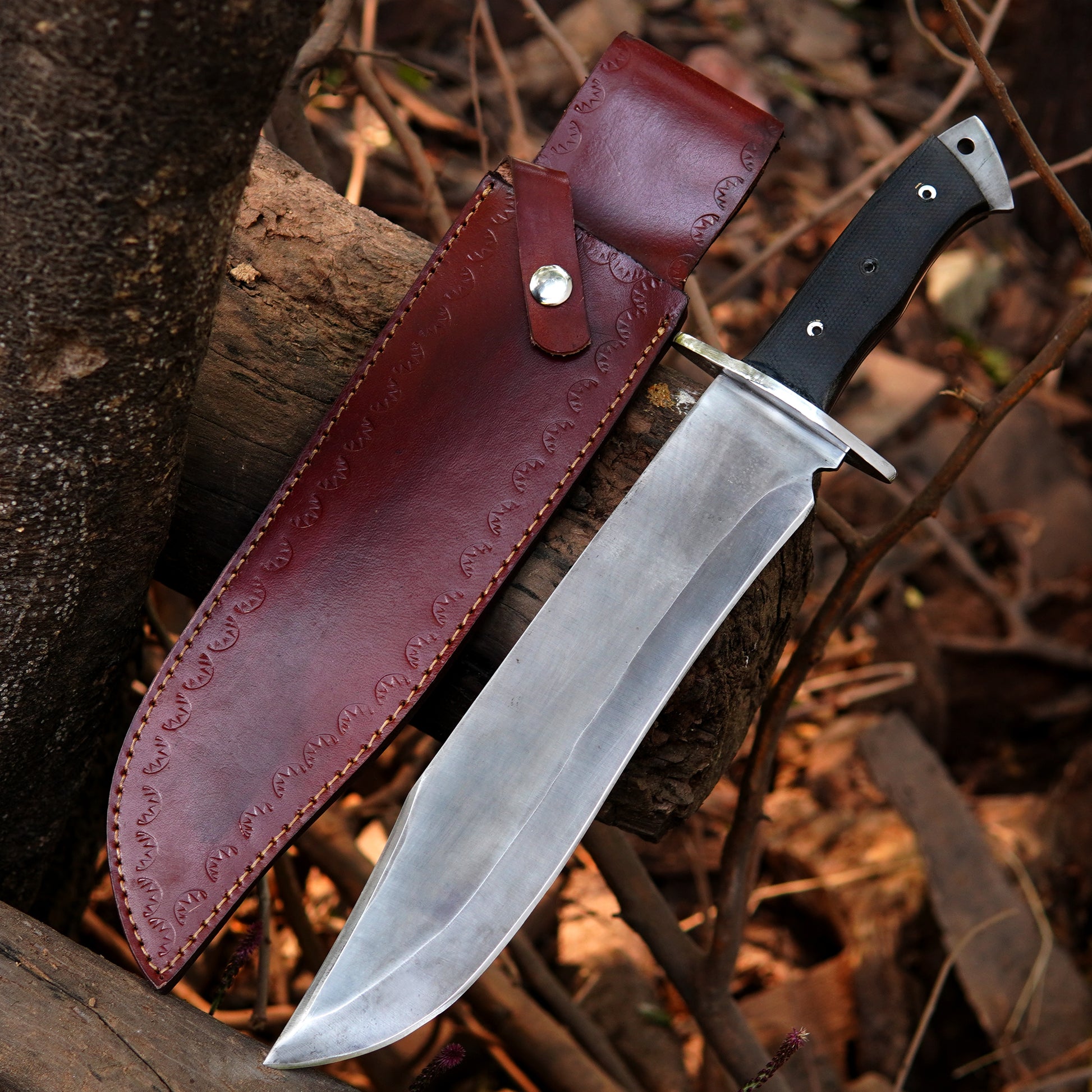 Handmade bowie style knife with polished steel blade and durable synthetic handle displayed on wood.