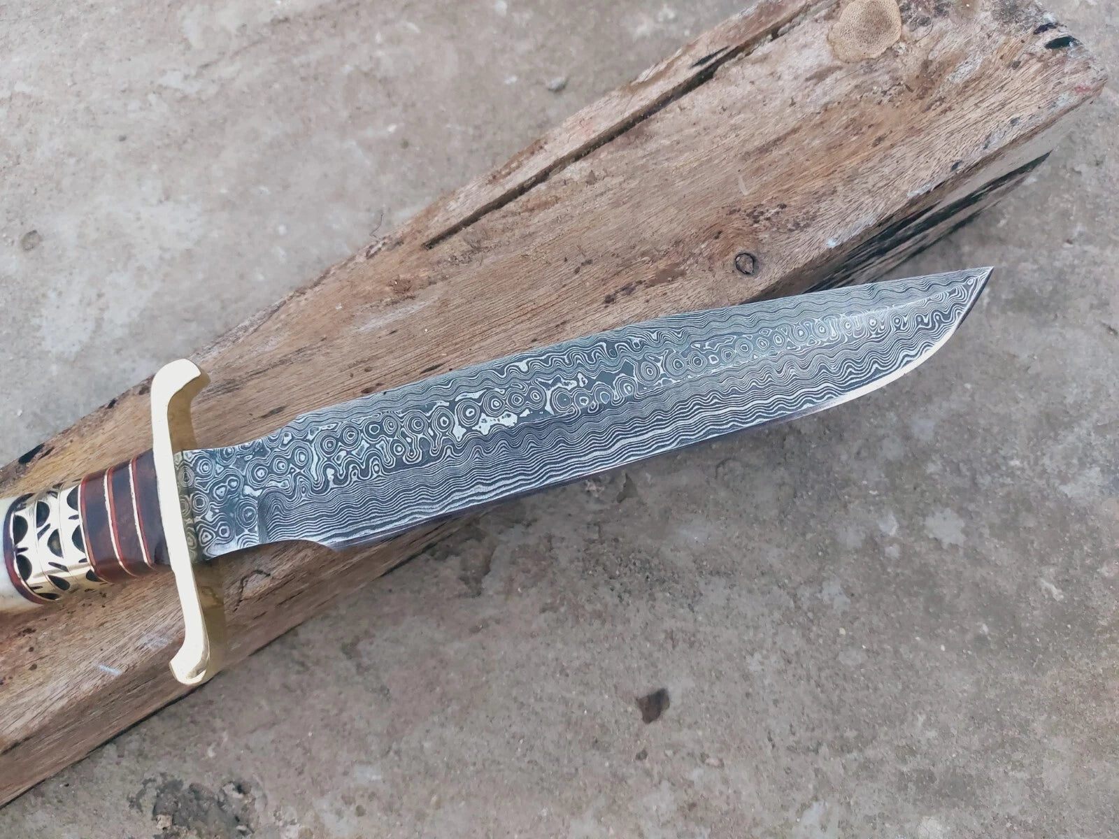 Handmade Damascus bowie knife with stag handle and brass spacer detailing. Each piece is forged with unique steel layers, delivering strength, sharpness, and traditional craftsmanship. Perfect for outdoors, hunting, or as a collectible knife.