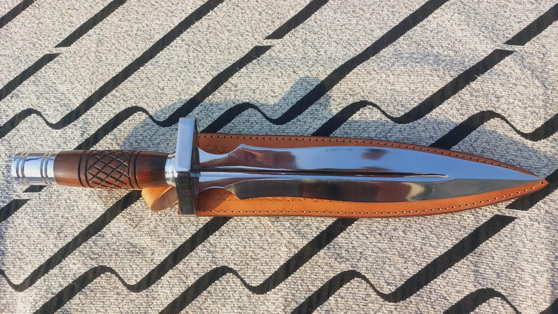 Double-edge dagger knife displayed with brown leather sheath.