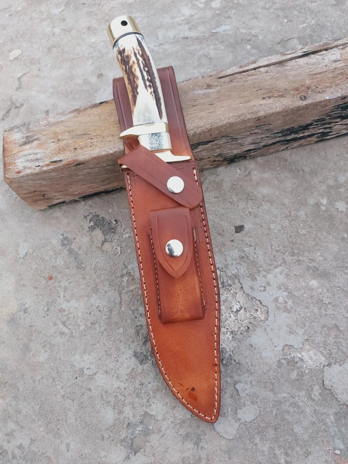 Damascus steel fixed blade hunting knife with stag antler handle, brass guard, and stitched leather sheath. Subhilt design provides better control during use. Perfect for hunters, campers, and survival enthusiasts.