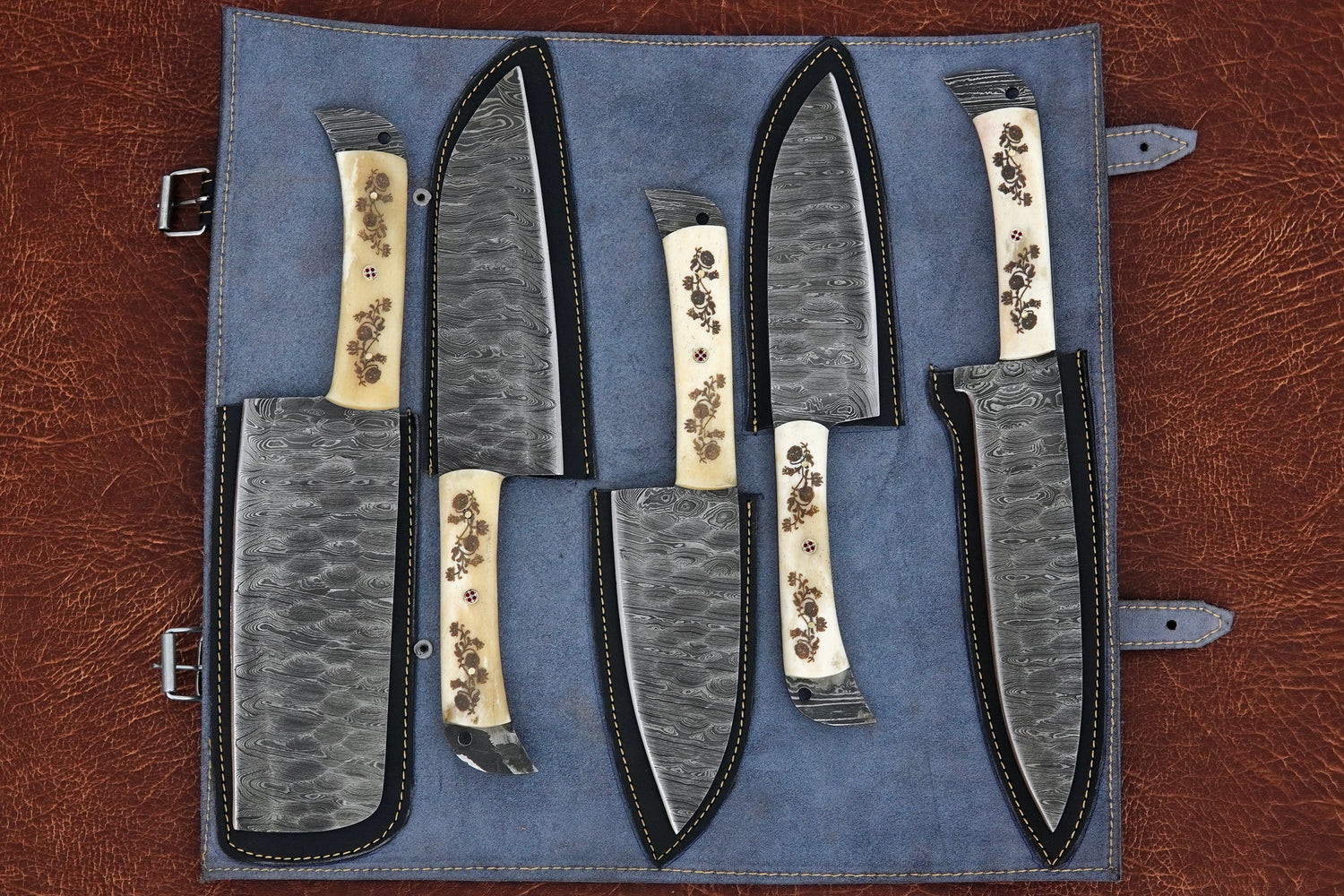 A custom handmade kitchen knife set of 5 pieces forged from Damascus steel with full tang blades and polished white natural material handles. This premium chef set includes a leather kit for safe storage. Free engraving makes it a personalised gift.