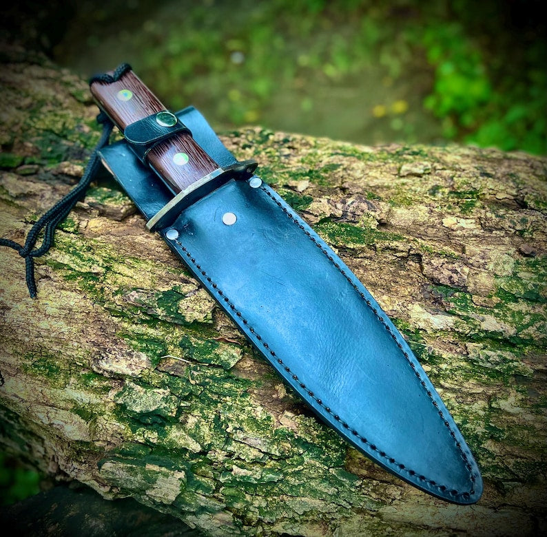 Handmade 5160 carbon steel hunting knife set with leather sheath, shown outdoors on a log.