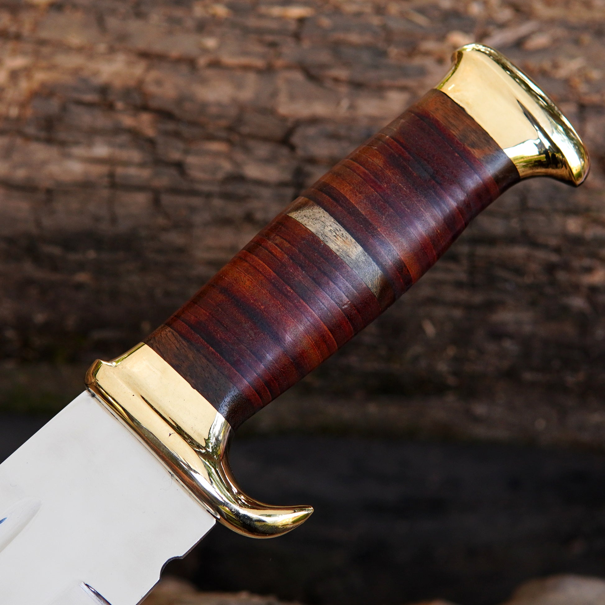Side view of the Bowie knife placed on rustic wooden logs, showing its full profile and elegant blade curve. The strong build and sharpened edge make it reliable for outdoor survival and camping needs. The solid construction ensures durability, while the included pure leather sheath protects the blade when not in use. This knife blends performance and craftsmanship, making it a standout addition to any collection.
