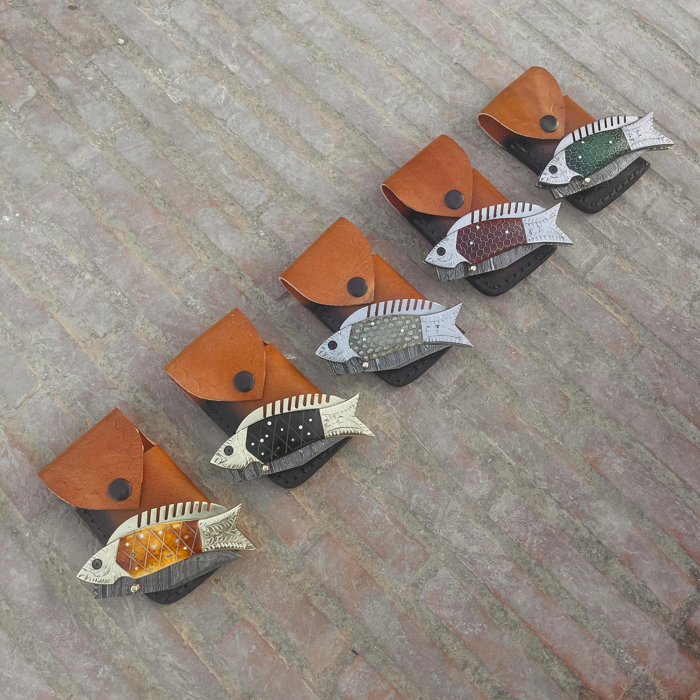 Outdoor photograph of fish Damascus pocket knife placed on leather pouch showing everyday carry knife style.