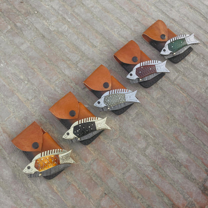 Outdoor photograph of fish Damascus pocket knife placed on leather pouch showing everyday carry knife style.