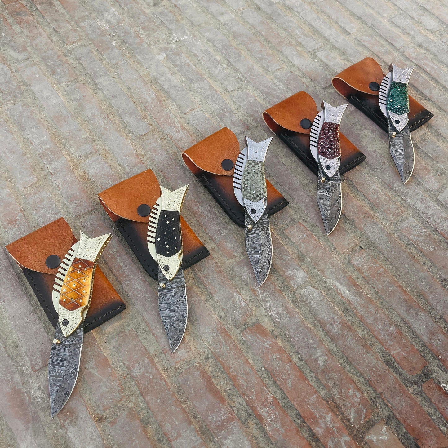 Damascus folding pocket knife open blade view showing patterned steel blade and fish style handle design.