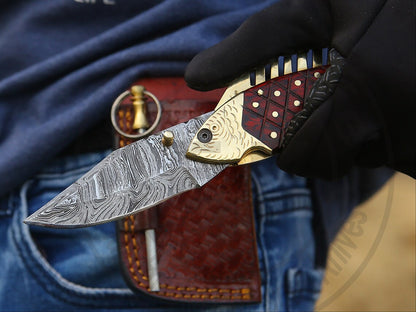 Collectible handmade fish-shaped folding knife with brass body and Damascus blade.