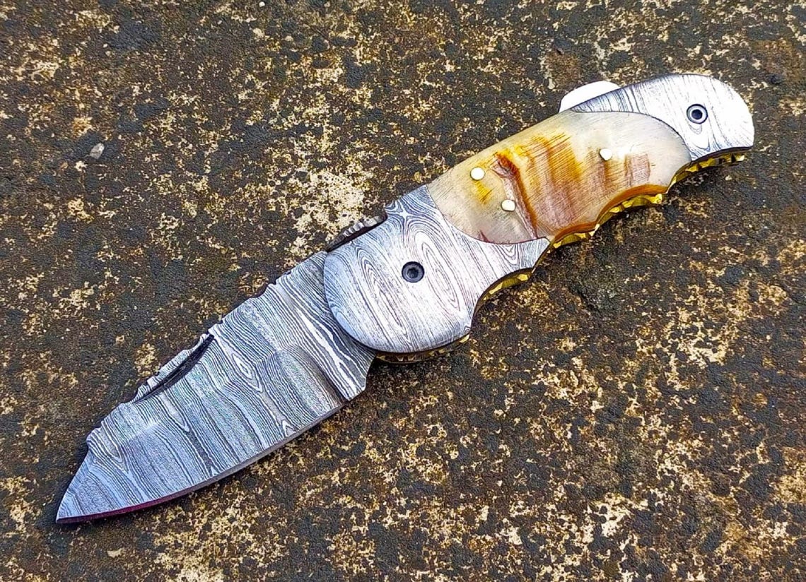 Side view of handmade Damascus knife featuring decorative file work and spine engraving.