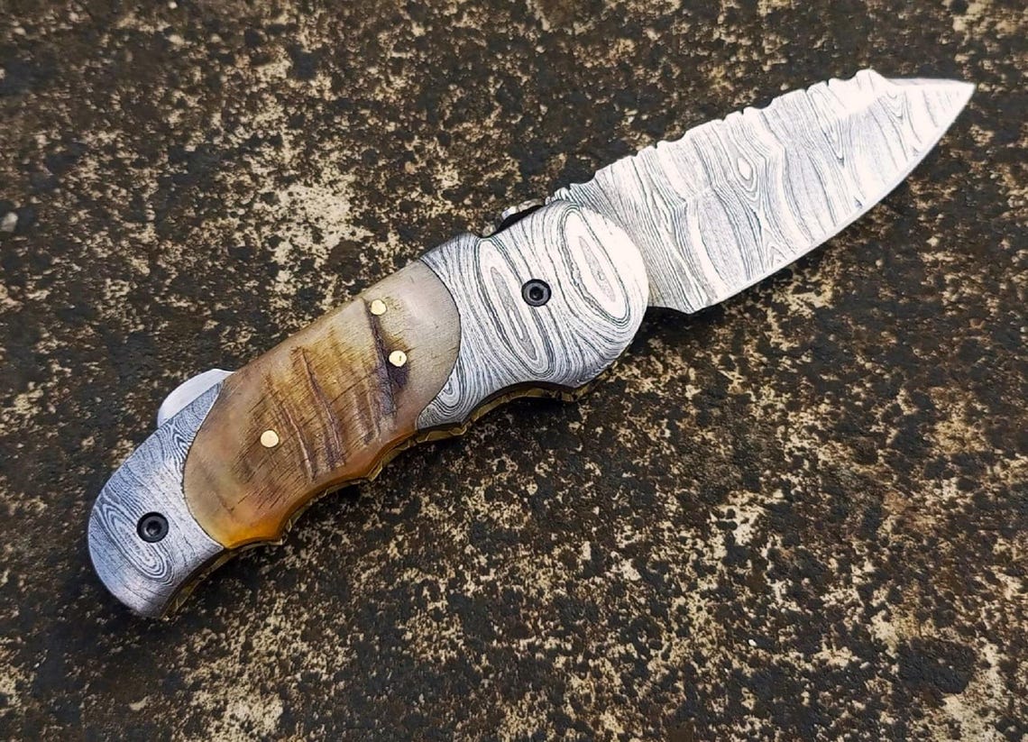 Open view of Damascus pocket knife showing full blade pattern and ergonomic handle grip.