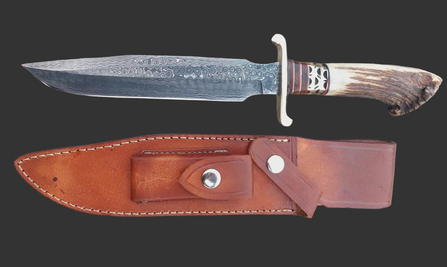 Handmade hunting bowie knife with Damascus steel blade showing unique patterns, stag crown handle for secure grip, and brass spacers adding strength and detail. Includes hand-stitched leather sheath, perfect for collectors, hunters, and outdoor adventurers seeking durability and style.