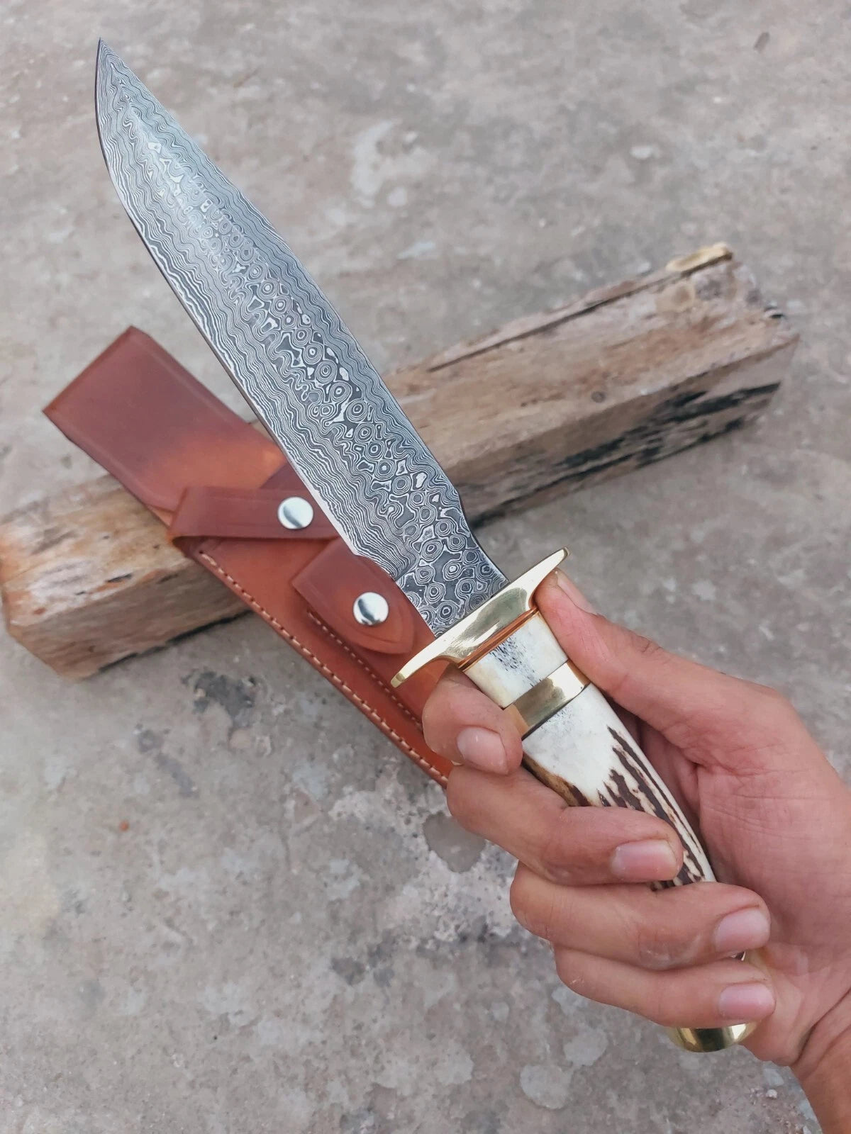 Handmade Damascus steel hunting knife with subhilt design, showcasing a unique layered blade pattern. The knife features a stag antler handle for a strong grip and includes a hand-stitched leather sheath for safe carry. Perfect for hunters, outdoorsmen, and collectors seeking craftsmanship and durability.