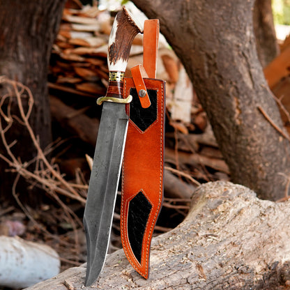Handmade damascus style bowie knife displayed outdoors on natural wood surface showing detailed patterned blade and ergonomic handle design. The image highlights craftsmanship, blade finish, and balanced structure suitable for camping, outdoor activities, collectors, and gift buyers searching for a premium handmade outdoor knife with leather sheath included.