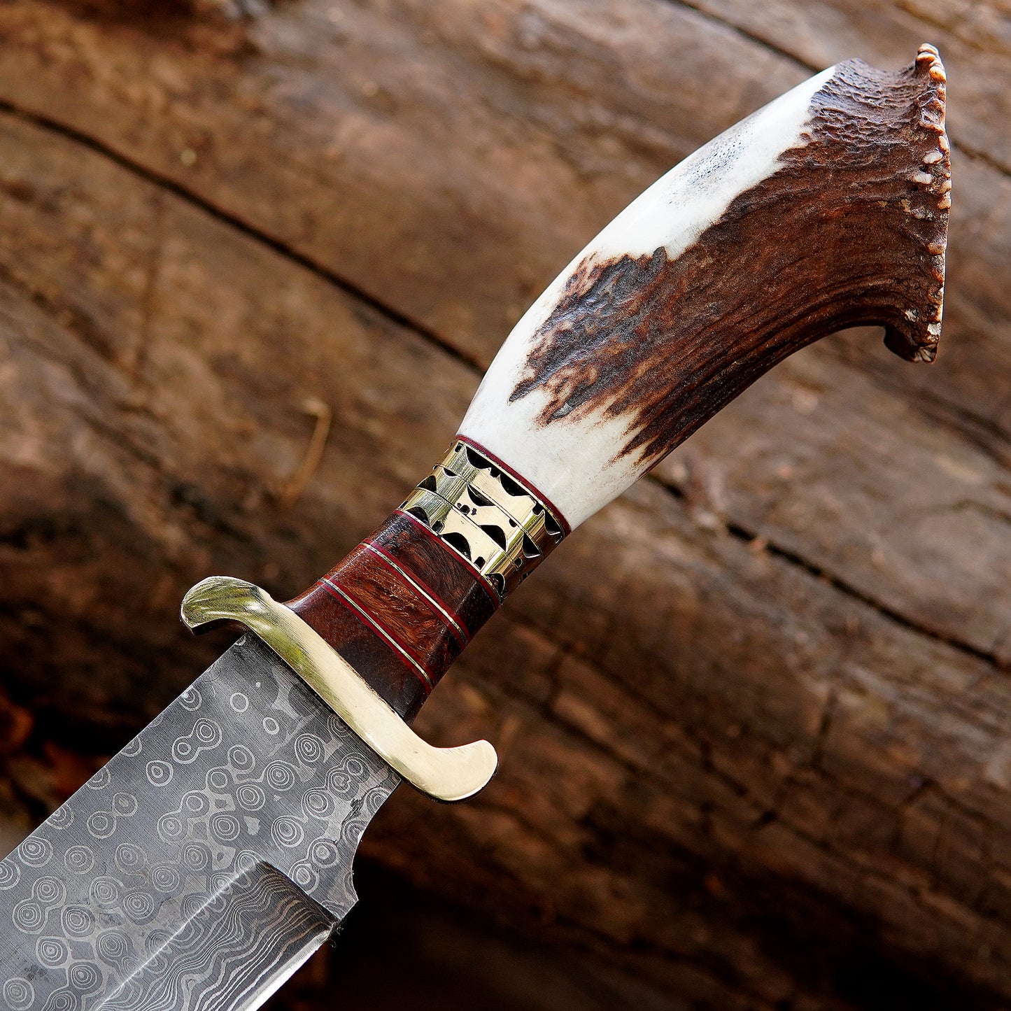 Damascus style patterned blade shown in natural outdoor environment focusing on steel texture and craftsmanship detail. The image communicates premium quality, handmade character, and collector appeal for buyers searching unique outdoor knives with traditional styling.