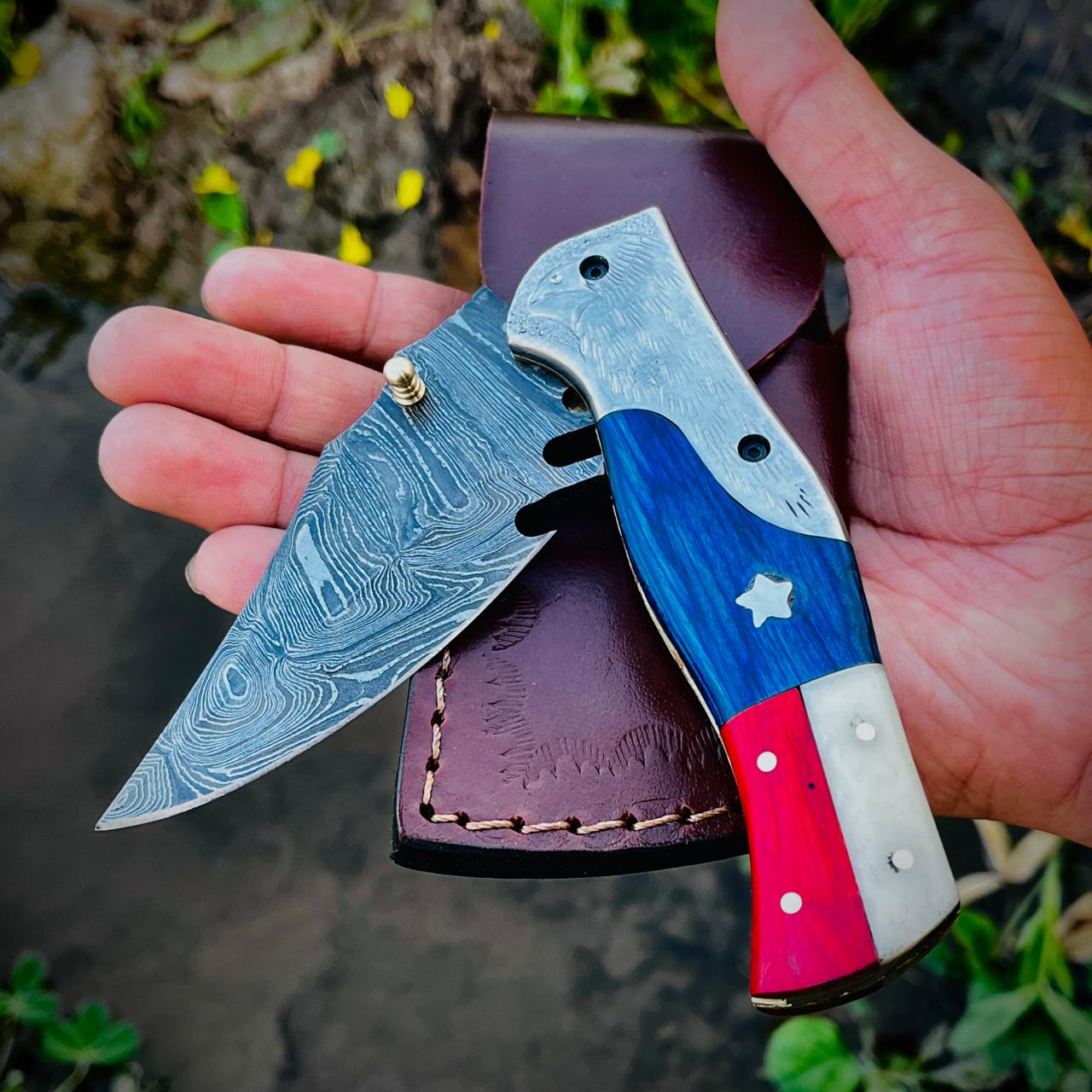 Detailed eagle bolster Damascus knife handle showing patriotic colored grip and engraved metal bolster.