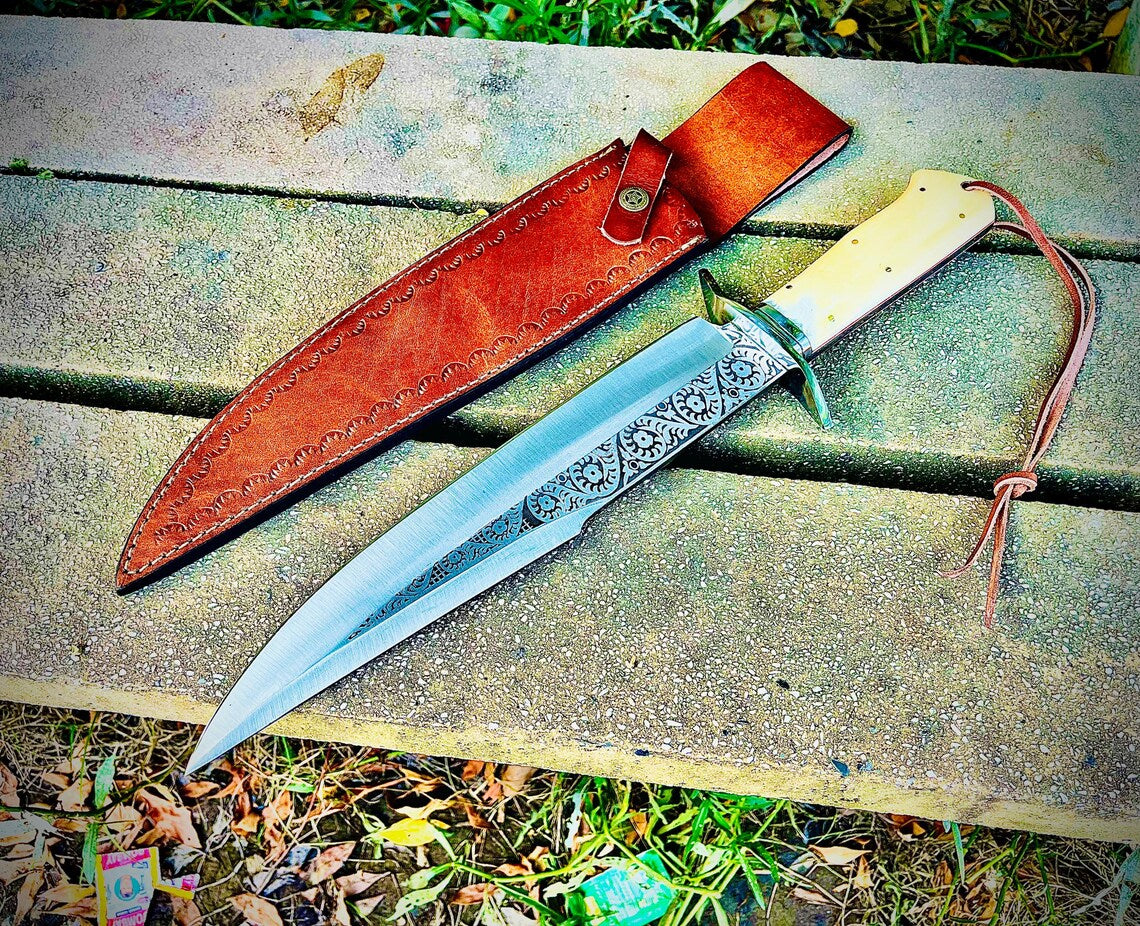Close-up of the engraved steel blade pattern on sandbar bowie knife with polished guard and leather strap.