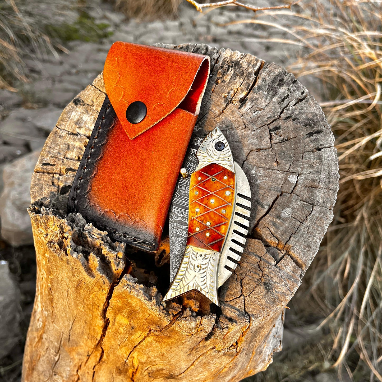 Leather sheath for Damascus pocket knife placed on wooden stump showing handcrafted leather texture and secure knife carrying option.