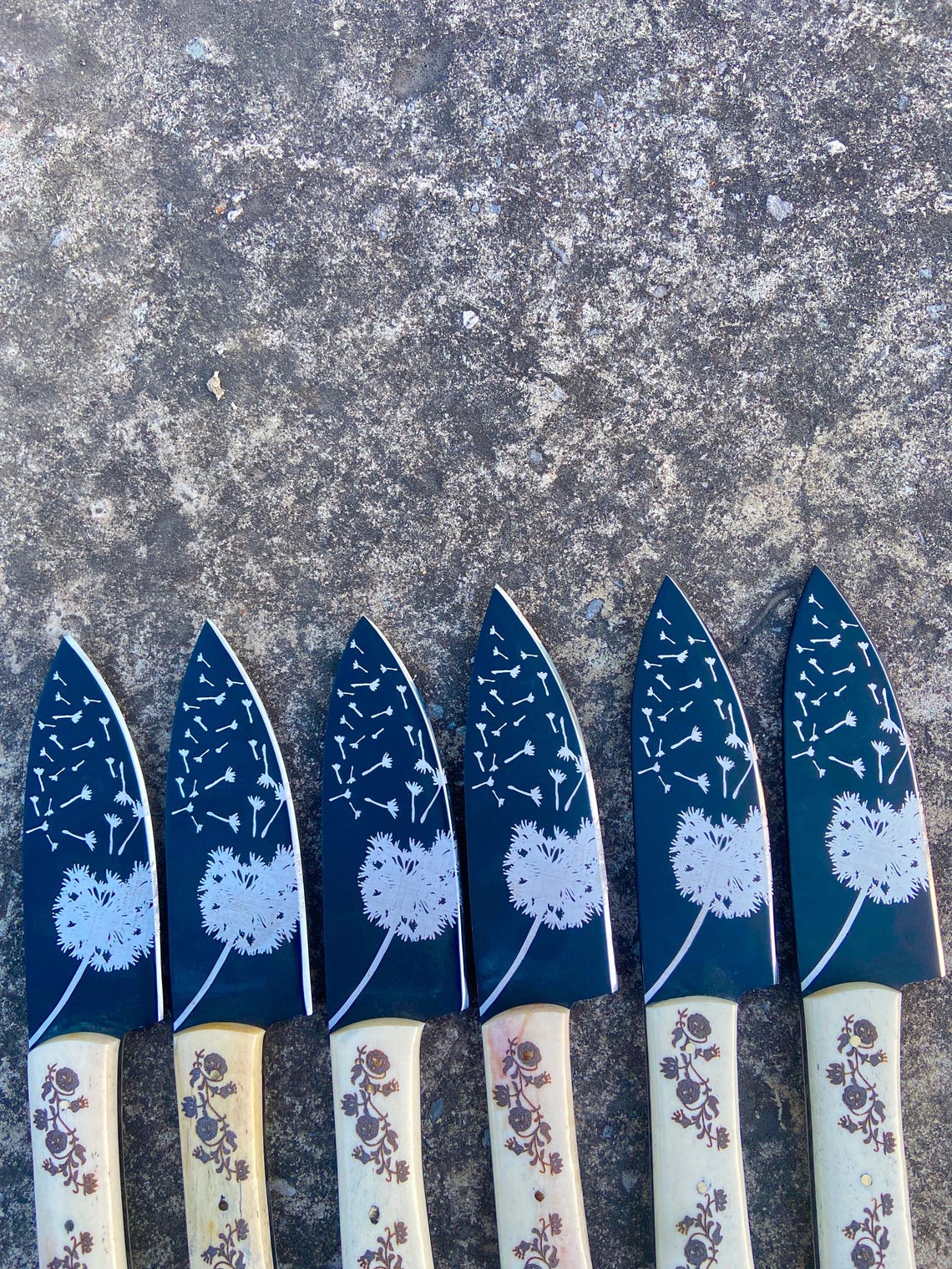 Floral engraved white handle knives laid on leather mat – ideal handmade gift for husband or mother.